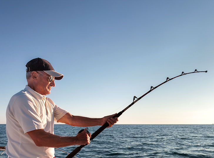 An older gentleman fishing off a boat.