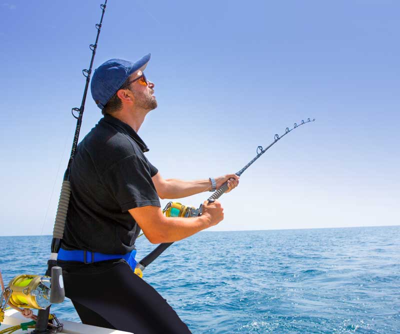 Man with Rod and Reel Deep Sea Fishing on Boat