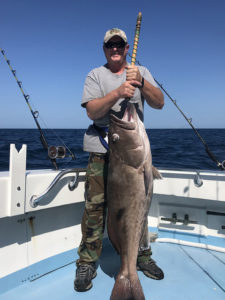 Man with fish caught aboard charter.